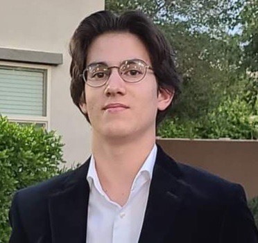 Armand Todoran wearing glasses with greenery and building in background